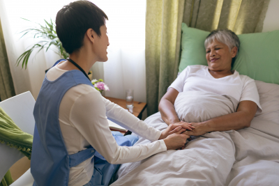 female nurse taking care of sick senior woman patient at home