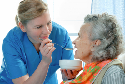 senior woman being fed by a nurse